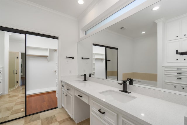 bathroom with a sink, recessed lighting, ornamental molding, and double vanity