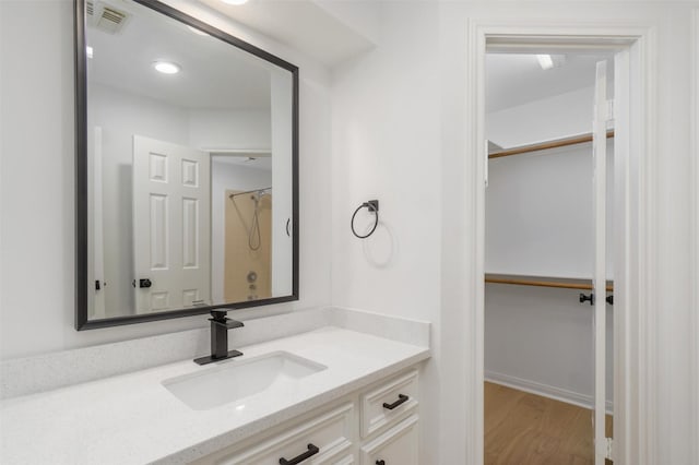 full bathroom featuring visible vents, baseboards, wood finished floors, vanity, and a shower