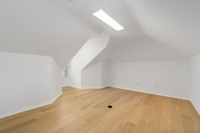 additional living space featuring baseboards, lofted ceiling, visible vents, and light wood finished floors