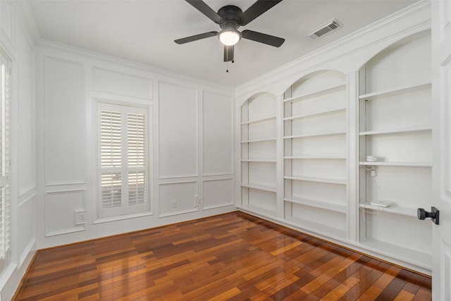 spare room with a decorative wall, a ceiling fan, and visible vents