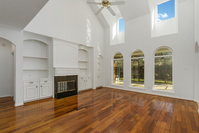 unfurnished living room with a fireplace, baseboards, dark wood-type flooring, and ceiling fan