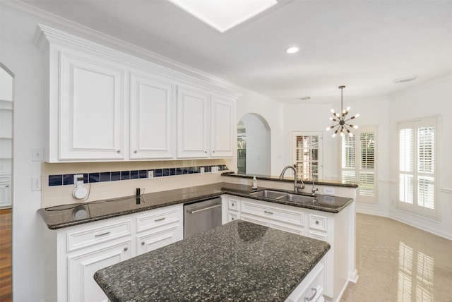 kitchen featuring dishwasher, a peninsula, an inviting chandelier, arched walkways, and a sink