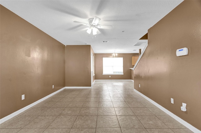 unfurnished room featuring light tile patterned floors, visible vents, baseboards, and ceiling fan with notable chandelier