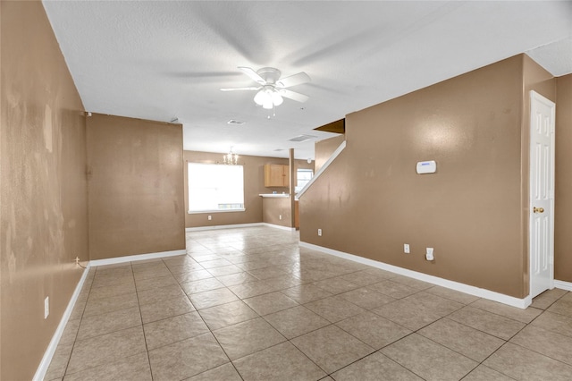 unfurnished room with visible vents, ceiling fan with notable chandelier, a textured ceiling, light tile patterned flooring, and baseboards