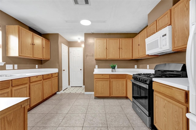 kitchen with white appliances, light tile patterned floors, visible vents, a sink, and light countertops