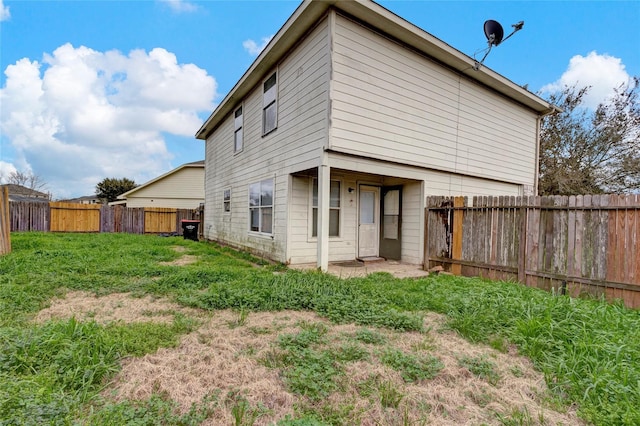 rear view of property featuring a yard and a fenced backyard