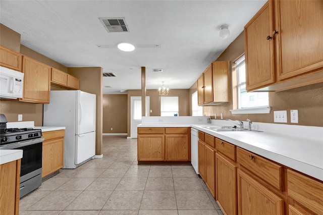 kitchen with visible vents, white appliances, a peninsula, and a sink