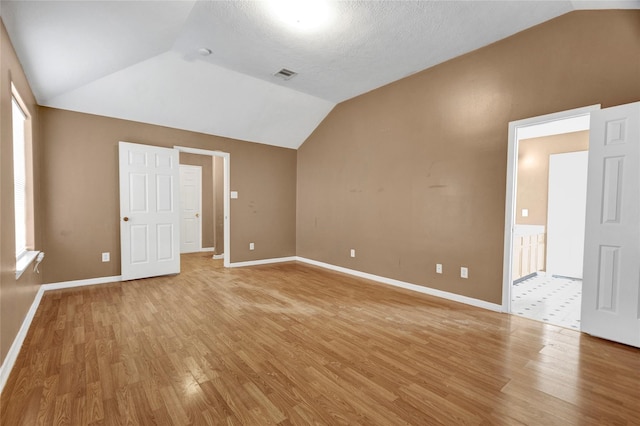 unfurnished room with lofted ceiling, visible vents, and light wood finished floors