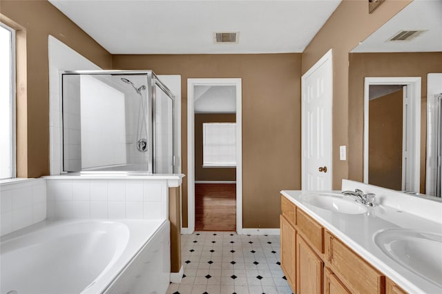 bathroom with a shower stall, a garden tub, visible vents, and a sink