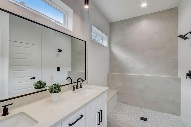 bathroom with double vanity, a tile shower, and a sink