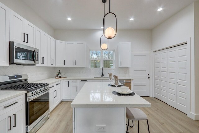 kitchen with a center island, light wood-style flooring, stainless steel appliances, and a sink