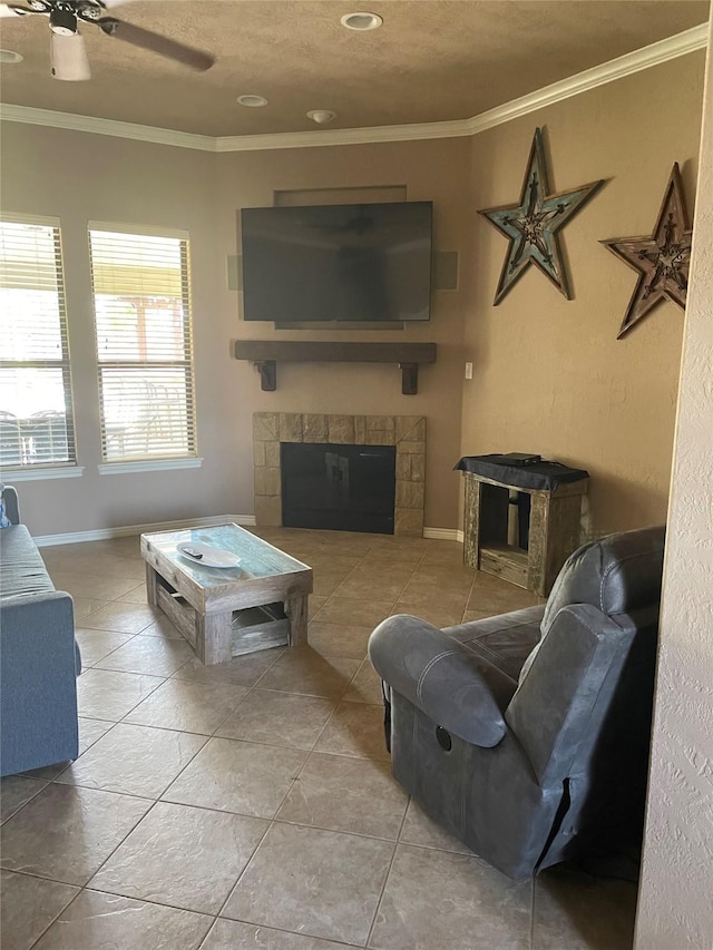 tiled living area with baseboards, ceiling fan, crown molding, and a tile fireplace