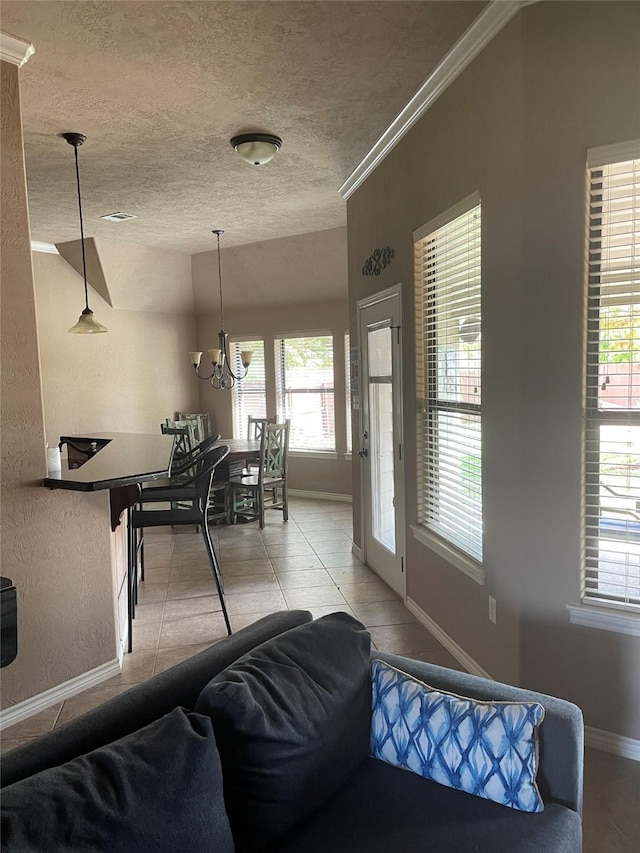 living area featuring a notable chandelier, light tile patterned floors, baseboards, and a textured ceiling