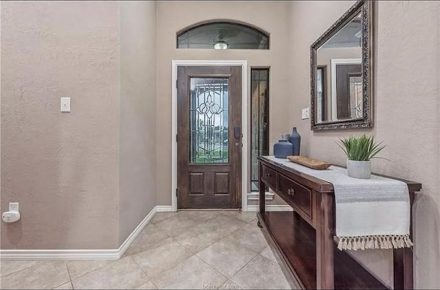 foyer entrance with light tile patterned floors, baseboards, and a textured wall