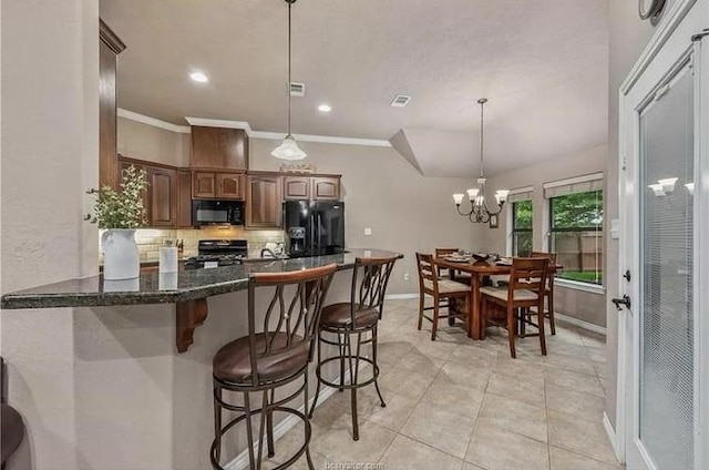 kitchen featuring backsplash, a kitchen breakfast bar, black appliances, and ornamental molding