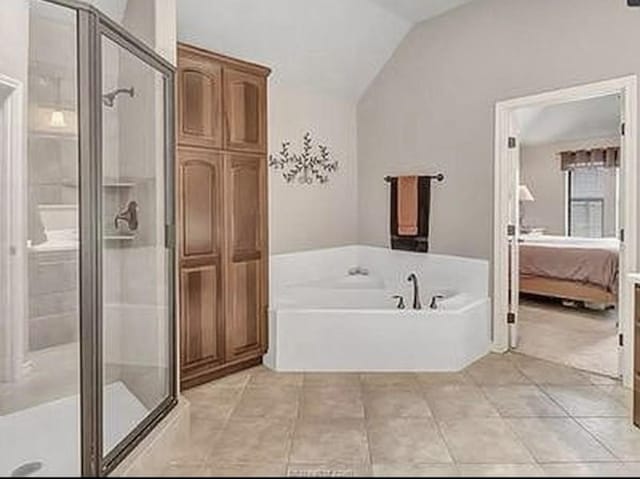 bathroom with lofted ceiling, a garden tub, ensuite bath, and a stall shower