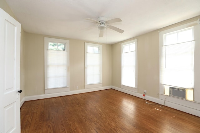 spare room featuring cooling unit, wood finished floors, baseboards, and ceiling fan