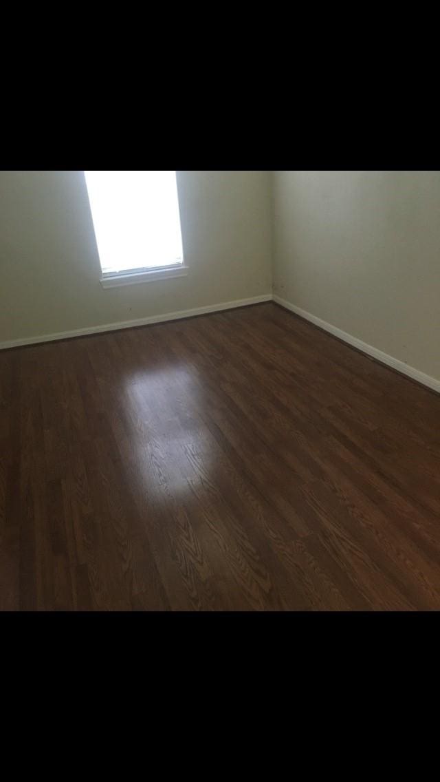 spare room with dark wood-type flooring and baseboards