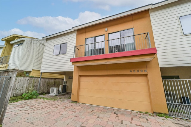 view of front of home featuring stucco siding, a patio, fence, a garage, and a balcony