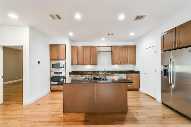 kitchen featuring visible vents, a sink, a kitchen island, stainless steel appliances, and light wood-style floors