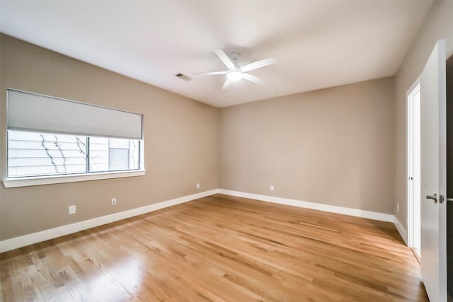 spare room with light wood-style flooring, a ceiling fan, visible vents, and baseboards