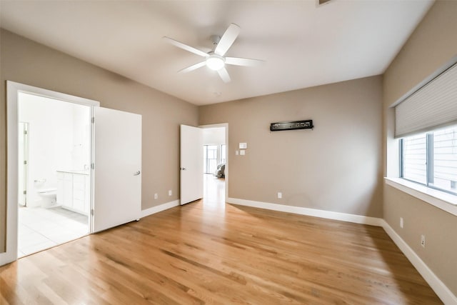 unfurnished bedroom with light wood-style flooring, ensuite bathroom, baseboards, and ceiling fan