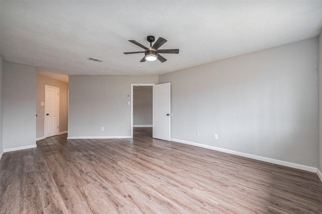 unfurnished room with visible vents, baseboards, ceiling fan, and wood finished floors