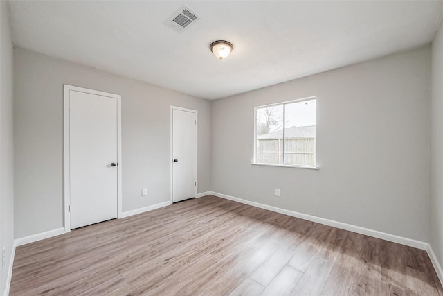 unfurnished bedroom with visible vents, baseboards, and wood finished floors