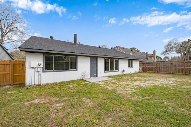 back of property featuring a lawn, a shingled roof, and a fenced backyard