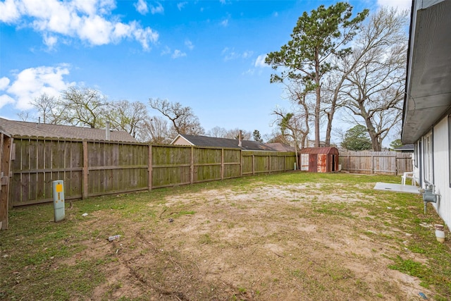 view of yard featuring a fenced backyard, a storage unit, and an outdoor structure