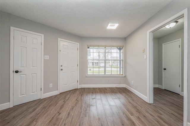 interior space featuring a textured ceiling, baseboards, and wood finished floors