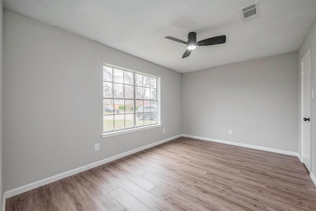 spare room featuring wood finished floors, a ceiling fan, visible vents, and baseboards