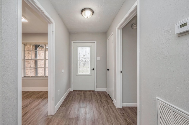 entrance foyer featuring visible vents, a textured ceiling, baseboards, and wood finished floors