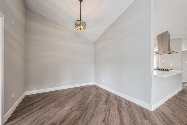 spare room featuring baseboards, wood finished floors, and vaulted ceiling