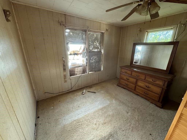 unfurnished bedroom with wooden walls and a ceiling fan