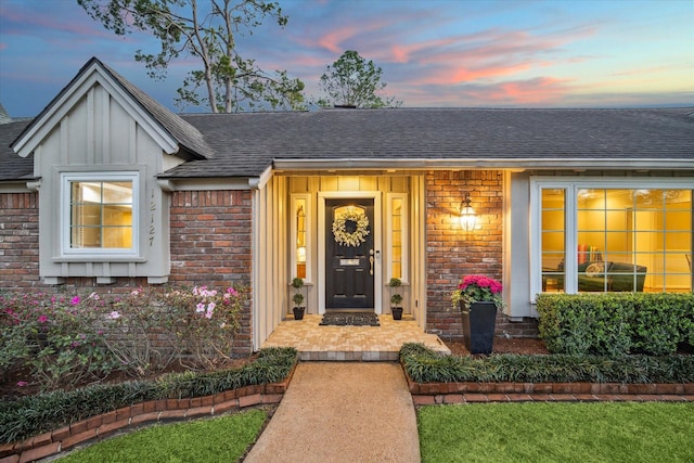 entrance to property featuring brick siding and a shingled roof