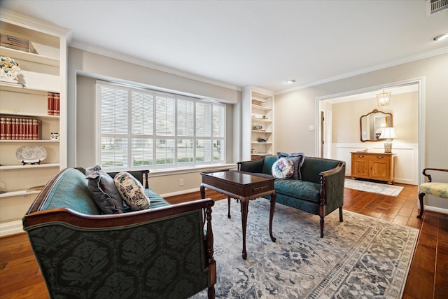 living area featuring visible vents, built in shelves, wood finished floors, and ornamental molding