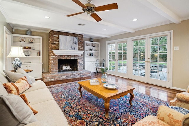 living area featuring wood finished floors, a ceiling fan, visible vents, beam ceiling, and ornamental molding