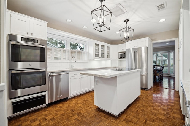 kitchen featuring visible vents, a sink, appliances with stainless steel finishes, a warming drawer, and a notable chandelier