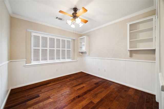 unfurnished room with a ceiling fan, visible vents, dark wood-style flooring, ornamental molding, and wainscoting