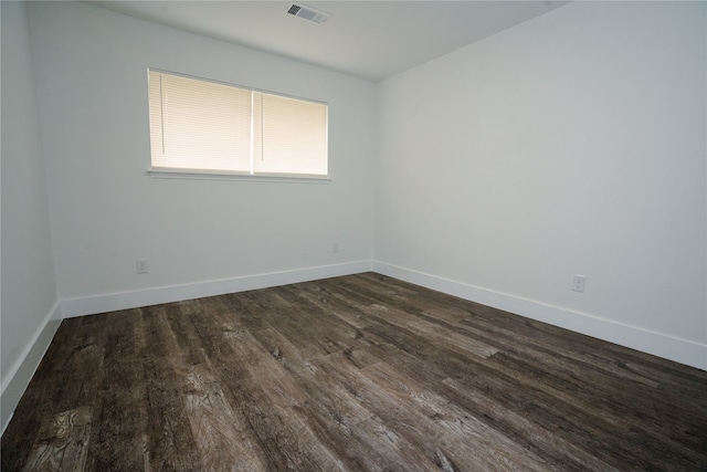 unfurnished room with dark wood finished floors, visible vents, and baseboards