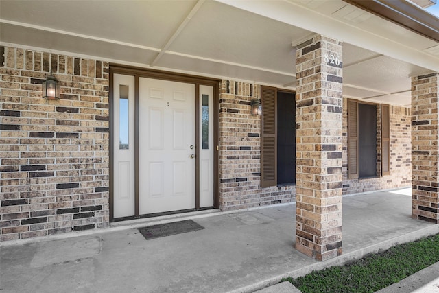 property entrance with a porch and brick siding