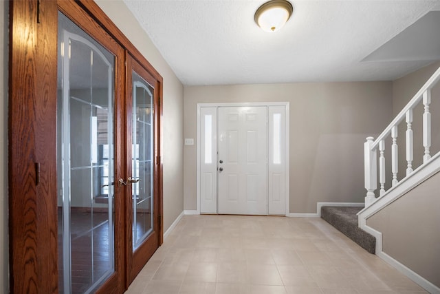 entrance foyer with stairway, french doors, and baseboards