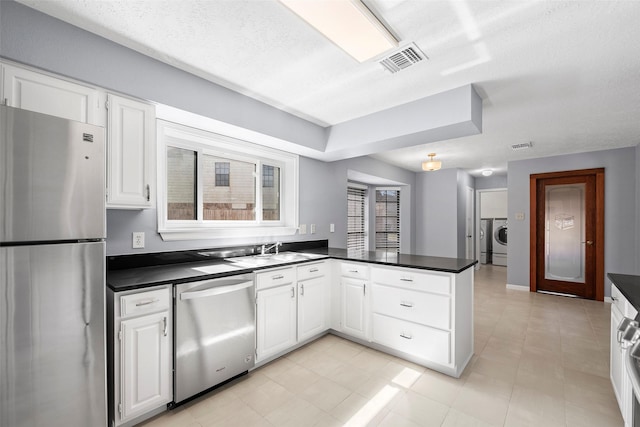 kitchen featuring visible vents, dark countertops, appliances with stainless steel finishes, and a peninsula