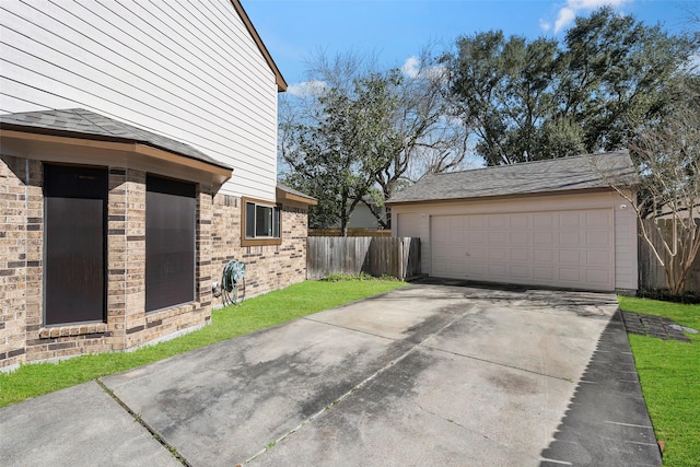 garage featuring concrete driveway and fence