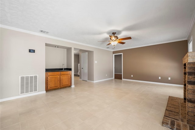 unfurnished living room with a sink, visible vents, ornamental molding, and a ceiling fan