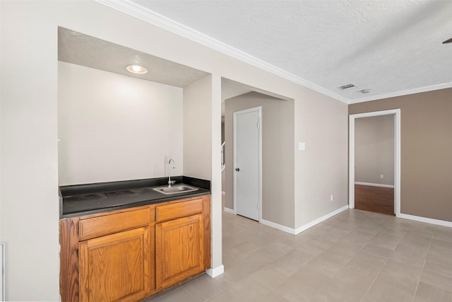 bar featuring visible vents, baseboards, a sink, a textured ceiling, and crown molding