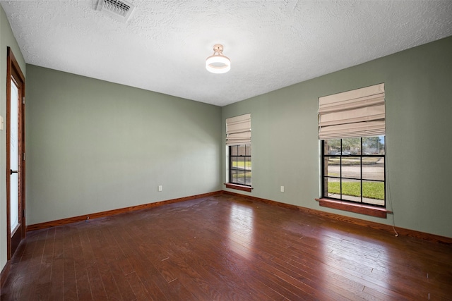 spare room with visible vents, wood-type flooring, a textured ceiling, and baseboards