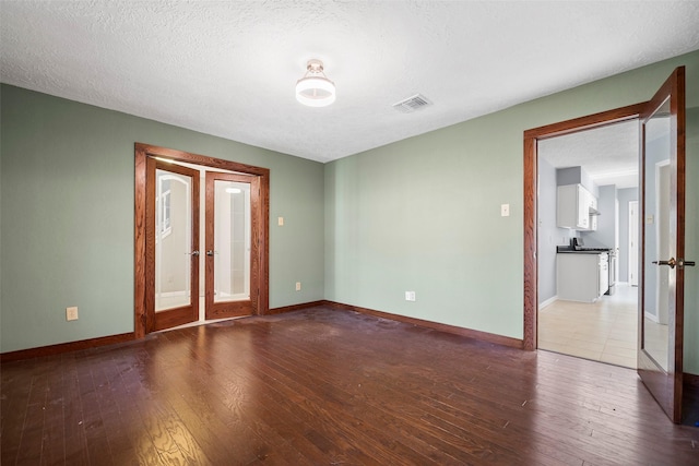 empty room featuring hardwood / wood-style floors, french doors, visible vents, and a textured ceiling