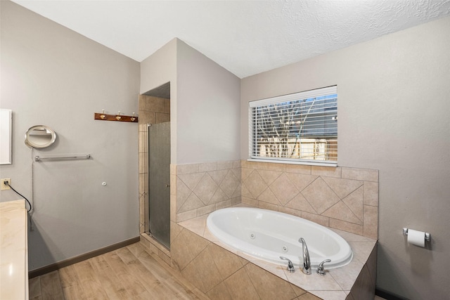 bathroom featuring wood finished floors, baseboards, a stall shower, a whirlpool tub, and a textured ceiling